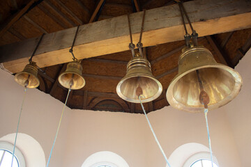 Large church bells. The bells are mounted on a wooden beam under the roof of the bell tower.
