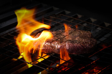 Grilled beef steak with flame on charcoal grill