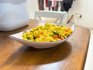 a plate of stir-fried yellow tofu with vegetables, served on a wooden table in a blue and white patterned bowl 