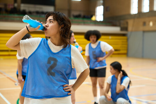 Female basketball player drinking isotonic drink after training
