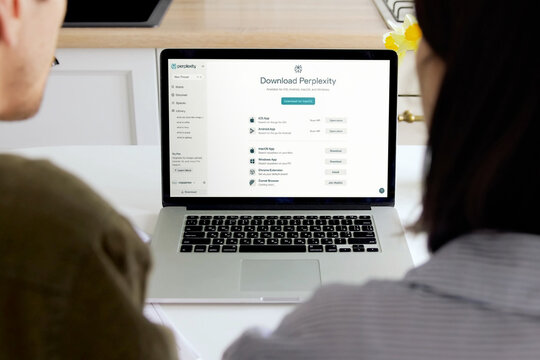 Coworkers installing perplexity ai application on laptop in office