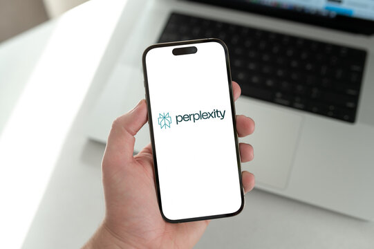 Hand holding smartphone displaying perplexity ai search engine logo
