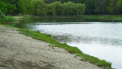Calm lake with forest around and open picnic zones for summer visitors