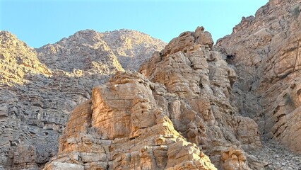 Ruined stone buildings rise from cracked desert soil beneath jagged ridges, capturing history of...
