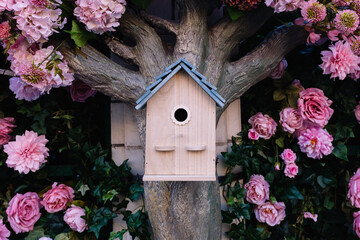 Wooden birdhouse hanging on blooming tree trunk