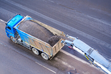 Machine cutting technique remove the old asphalt from the road, loads the waste into the body of...