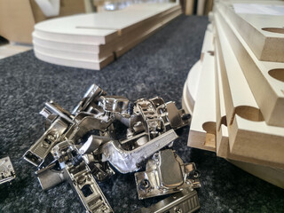 Assembly of furniture components with hardware and cut wood pieces in a workshop setting