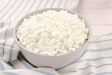 Farm cheese in a bowl on a light wooden background.