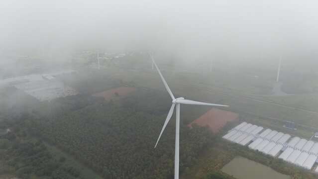 Fog moves towards wind turbines under clean energy rain clouds
