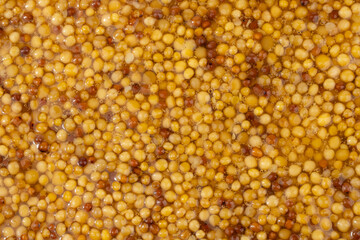 French Dijon mustard in a metal spoon, top view on mustard grains background. Gastronomy concept, organic food. Sauce. Slow rotation in a circle.	