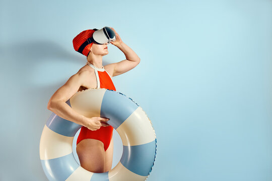 Woman in retro swimsuit with VR headset and swimming ring against blue background