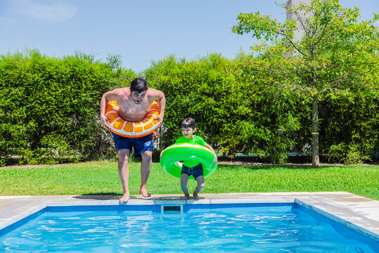Father and son having fun diving into a pool on a sunny day in Argentina