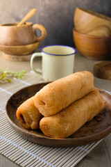 Traditional Asian molen snack, fried banana pastry on wooden plate, rustic background, perfect for culinary, food blog, recipe illustration, traditional dessert, bakery, or snack content