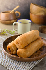Traditional Asian molen snack, fried banana pastry on wooden plate, rustic background, perfect for culinary, food blog, recipe illustration, traditional dessert, bakery, or snack content