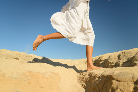 Woman running barefoot on sand in a desert setting