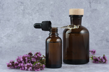 Dripping of organic essential oils, herbal extracts amber bottle, with fresh thyme flowers....