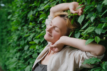 Woman enjoying nature against a green leaves wall, symbolizing mental health and work-life balance.
