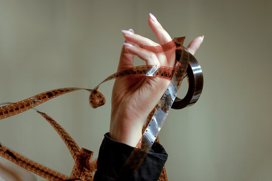Closeup of a hand entwined with vintage film tape representing nostalgia and cinema
