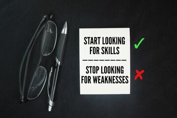 Glasses, pen and paper with words of motivation and inspiration Start looking for skills Stop looking for weaknesses