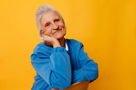 Smiling woman in blue jacket against yellow background