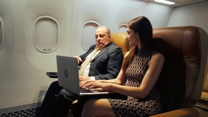 Two airline passengers using a laptop in-flight, showcasing onboard WiFi and inflight entertainment in a premium cabin, ideal for business travel, productivity, and digital connectivity services.