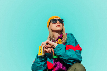 Woman in 80s style tracksuit with music cassette and headphones outdoors