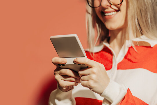 Smiling woman playing on a retro portable gaming console indoors
