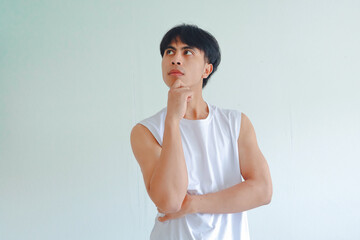 Portrait of a young Asian man from Southeast Asia with hand on chin in thoughtful pose, isolated on white background, representing thinking and contemplation