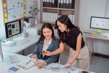 Two asian businesswomen are collaborating on a project, analyzing financial data and discussing...