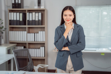 Young businesswoman contemplating with hand on chin while posing confidently in her office,...