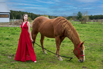 A young woman in a red dress with a horse