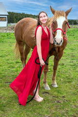 A young woman in a red dress with a horse
