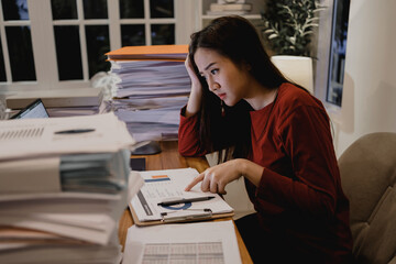 Asian businesswoman working hard late hours with a lot of document at home. Busy and exhausted of...