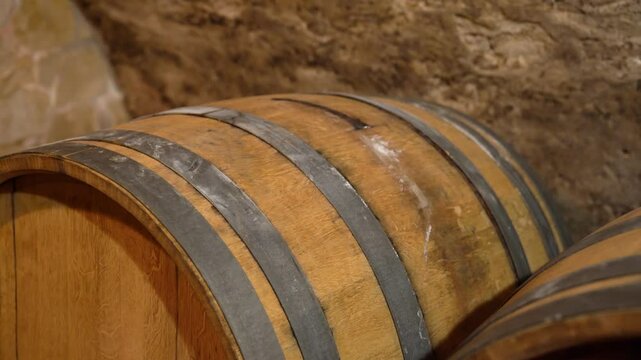 Close-up of old oak wine barrel with metal bands in wine cellar aging room
