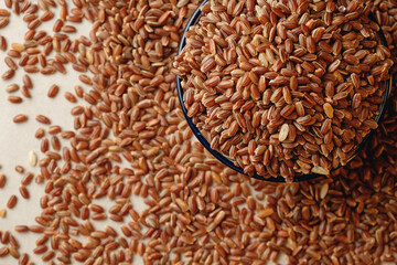 Organic brown rice overflowing from bowl in rustic kitchen setting