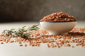 Organic brown rice in a rustic bowl with rosemary on a textured surface