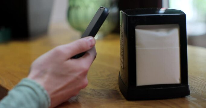 Unrecognizable man scanning QR code on table in restaurant or cafe. Online menu for clients. Convenience, contactless concept.
