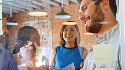 Businessman Writing Ideas On Glass Screen During Meeting