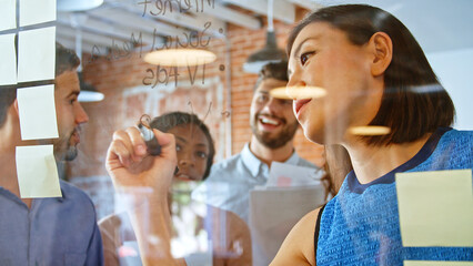 Businesswoman Writing Ideas On Glass Screen During Meeting