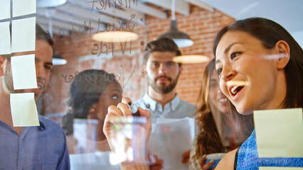 Businesswoman Writing Ideas On Glass Screen During Meeting