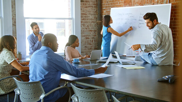 Businesswoman At Whiteboard In Brainstorming Meeting With Colleagues