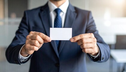 Fototapeta premium A man in a classic suit showing a blank business card with both hands, neutral background, business portrait without showing the face.