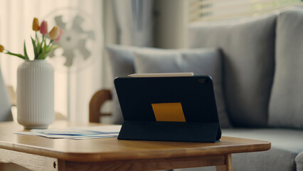 Digital tablet with stylus placed on wooden coffee table in cozy home setting. Modern lifestyle,...