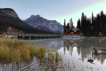 Fototapeta premium Building at the Emerald Lodge peninsula bridge end on Emerald Lake, clear dawn backed by peaks (L-R) Emerald-President-Michael. Yoho NP-BC-Canada-283