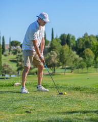 Golfer concentrating on putting on sunny golf course