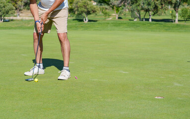 Golfer putting ball on green during sunny day