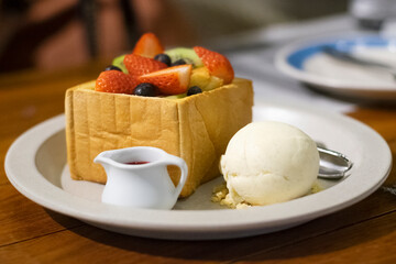 ice cream dessert, Vanilla ice cream with mixed fruits honey toast in white dish on wooden table close up 