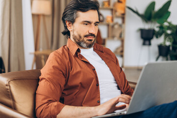 Focused freelancer working remotely from home office using laptop