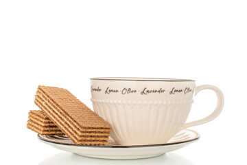 Sweet waffles on a ceramic saucer with a cup, close-up, isolated on a white background.