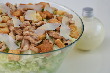 Classic Chicken Caesar Salad in a clear glass bowl with crisp lettuce, tender grilled chicken pieces, croutons, and Parmesan cheese closeup side view of refreshing salad